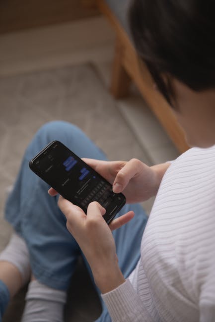 Asmuo žiūri į telefono ekrano laiko statistiką (juose matomi skaičiai)