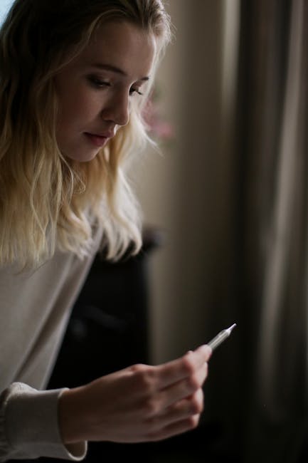 Moteris prie virtuvės stalo užsirašo skausmo ir nuovargio įvertinimus sąsiuvinyje